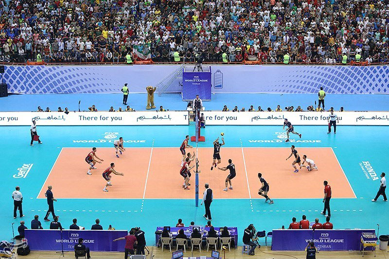 Equipo de vóley disputando un punto en un coliseo lleno