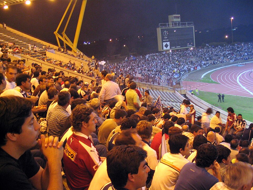 Hinchada en estadio argentino durante partido nocturno