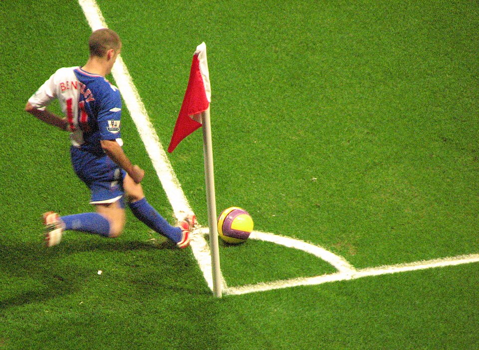 Jugador ejecutando un saque de esquina en un estadio